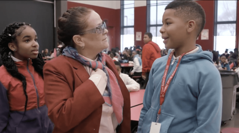 Teacher talking with boy one on one in busy classroom