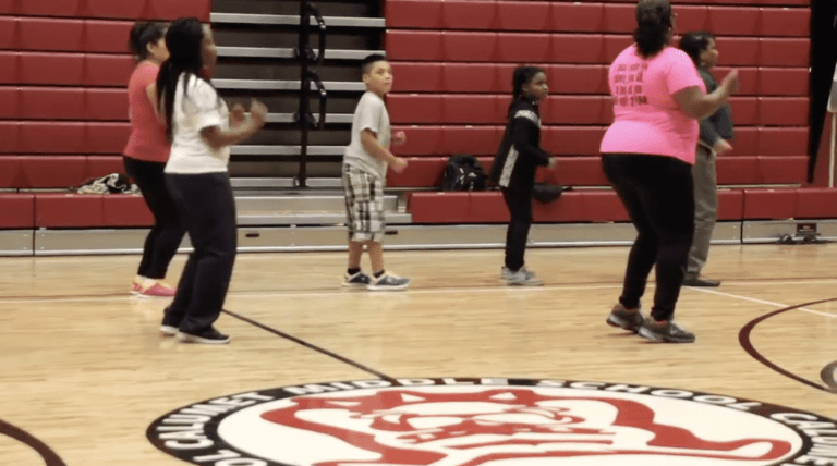Teacher dancing with students on gymnasium floor
